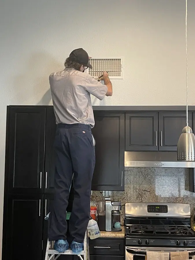 Technician inspecting an air vent during HVAC service in Willow Springs